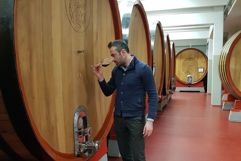 Wine maker wine tasting with large wine barrels